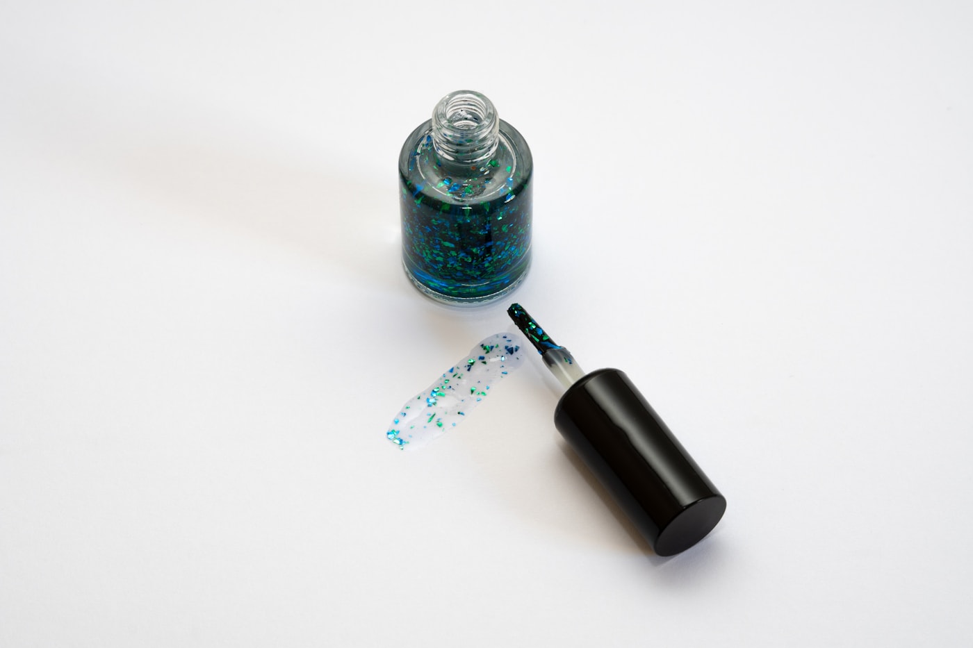 A bottle of nail polish sitting next to a bottle of glitter